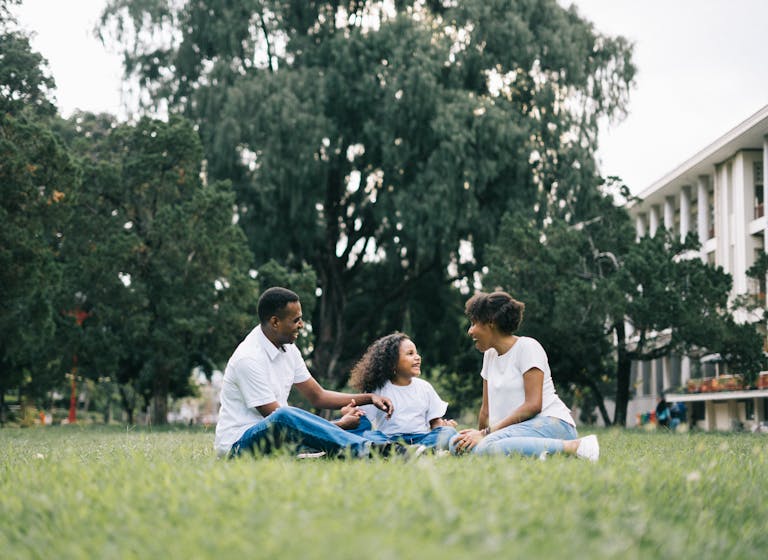 A happy family enjoying quality time together outdoors in a lush green park, meant to represent term life insurance.