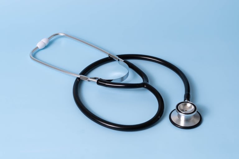 Close-up of a classic stethoscope on a blue background, symbolizing healthcare and medical profession.